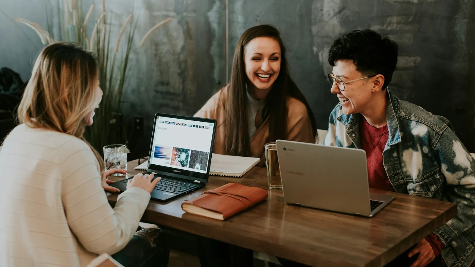 Drie mensen werken lachend samen aan een tafel